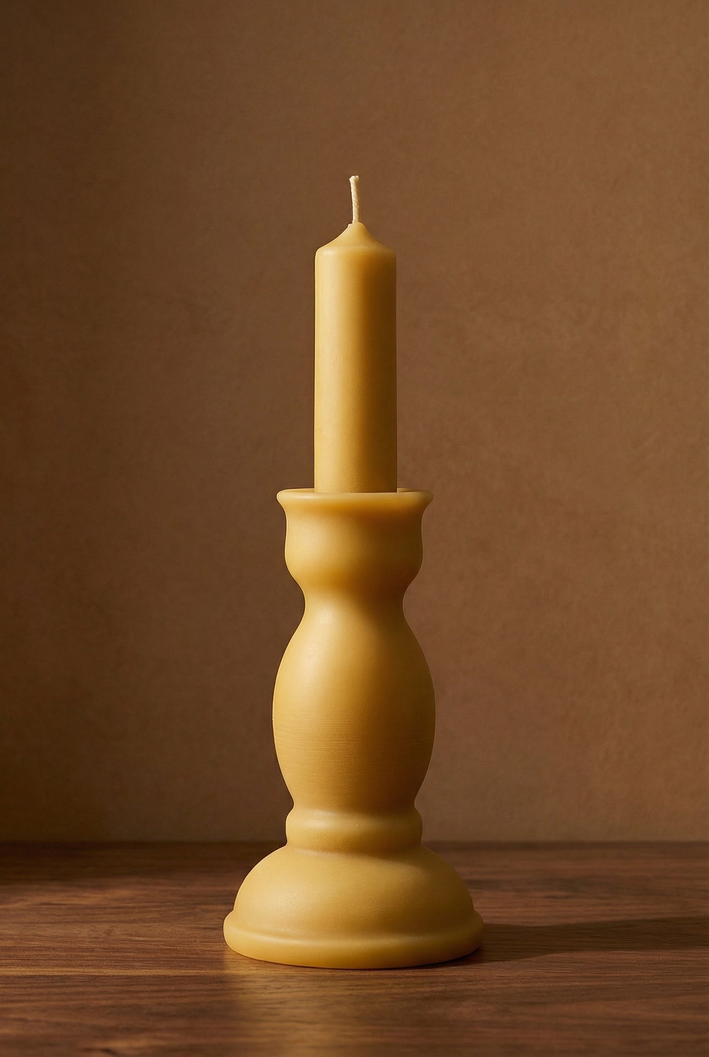 pillar beeswax candle sculptural form against a brown background