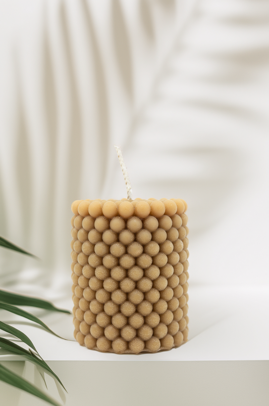 Beige textured candle on a white surface with a soft background